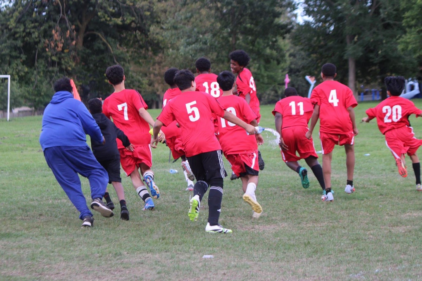 Young players and a coach run to celebrate together